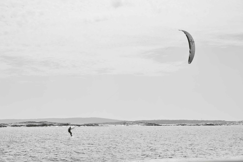 A person windsurfing on a beach with a large kite in the sky. 5