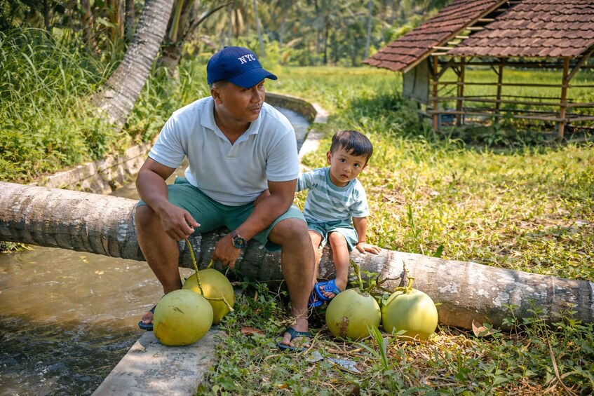 A man and a child near a water body with coconuts. 4