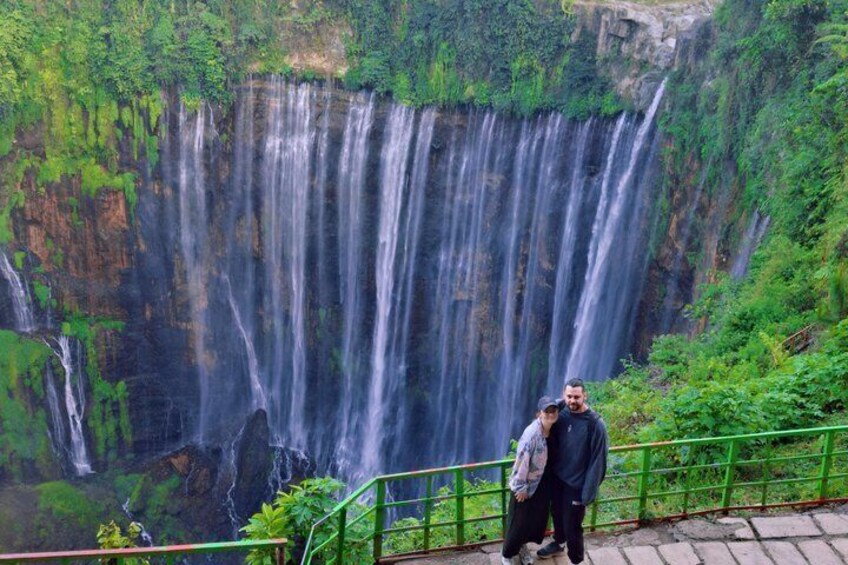 A waterfall cascading down a cliff surrounded by lush greenery. 1