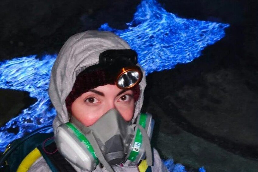 En person med hjälm och gasmask står framför en grotta som är upplyst med blått ljus. 2
