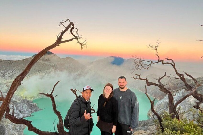 Three people standing on a mountain with a sunset in the background. 2