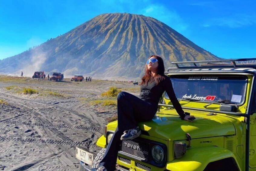 A person sitting on a yellow vehicle with a mountain in the background. 5