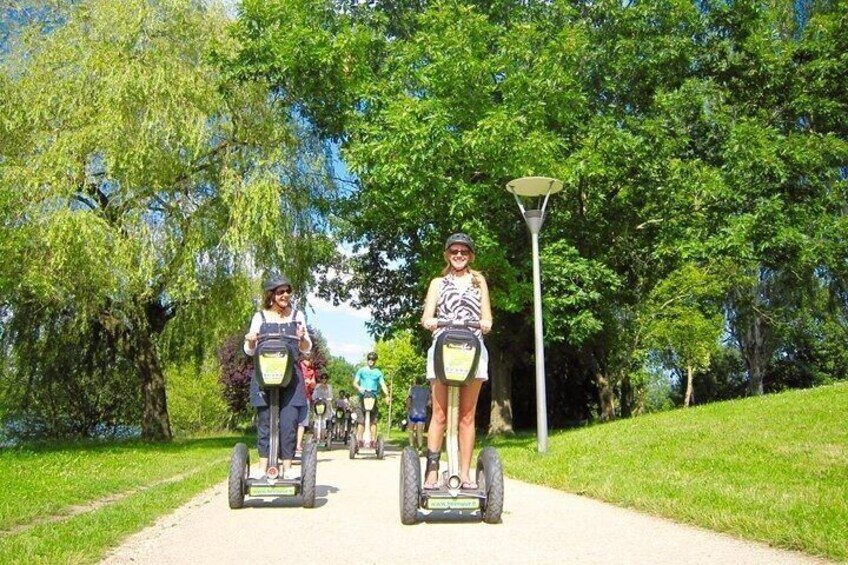 People on Segways on a paved path surrounded by trees. 1