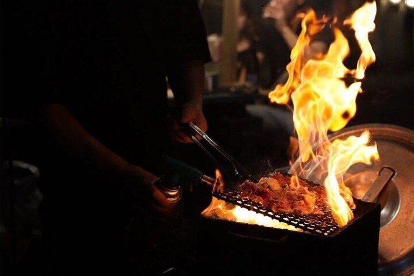 A person grilling food over an open flame. 5