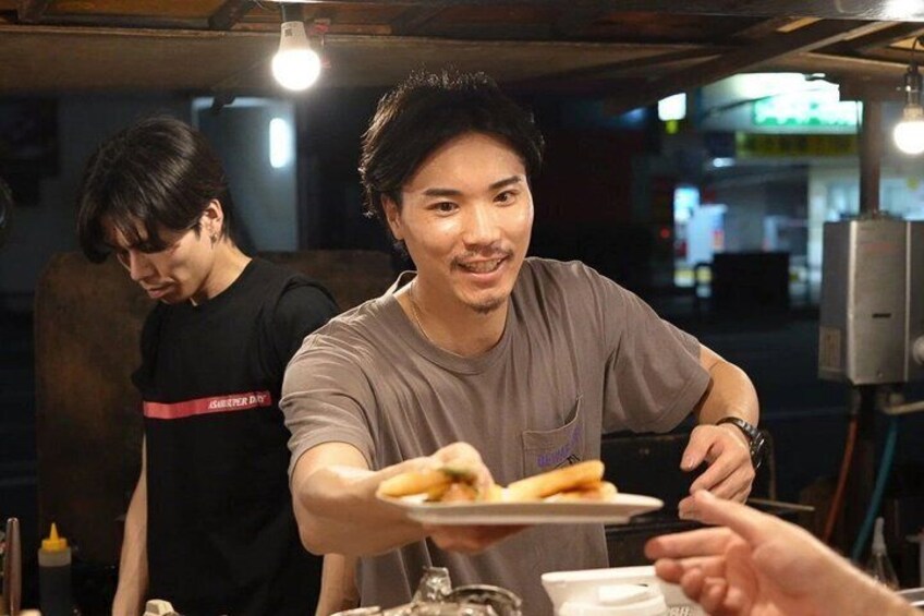 A person serving food at a table with another person in the background. 4