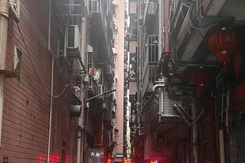 A narrow alleyway between buildings with visible air conditioning units and pipes. 3