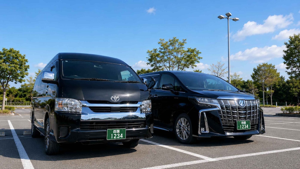 Two black Toyota SUVs parked in a parking lot with trees and a clear sky in the background. 5