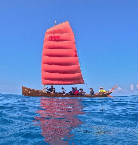 A traditional sailboat with a red sail on calm blue waters. 5