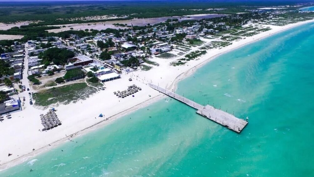 An aerial view of a coastal town with a pier extending into turquoise waters, surrounded by sandy beaches and residential areas. 4