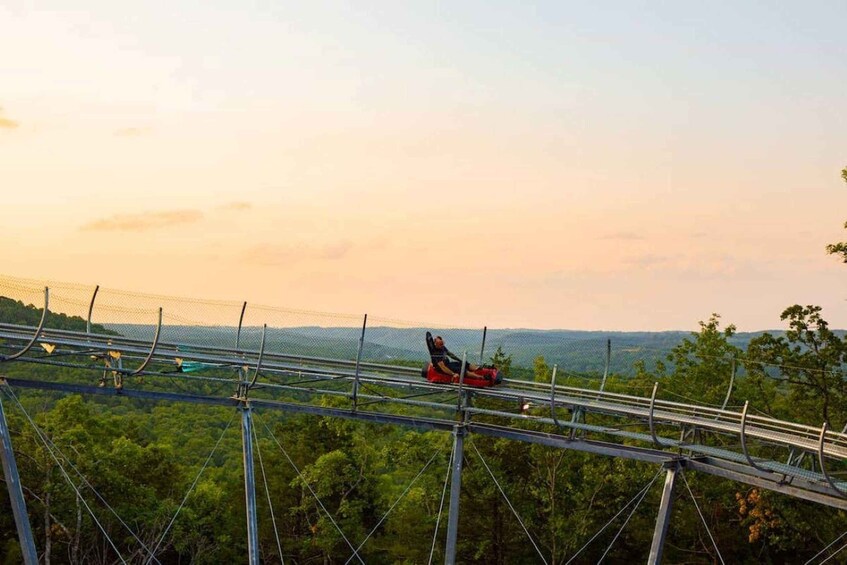 A person on a zip line over a forested area with a clear sky. 3