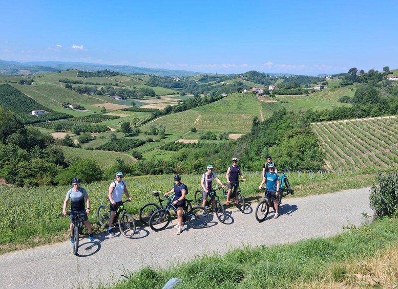 A group of cyclists on a paved path with a scenic view of rolling hills and vineyards. 1