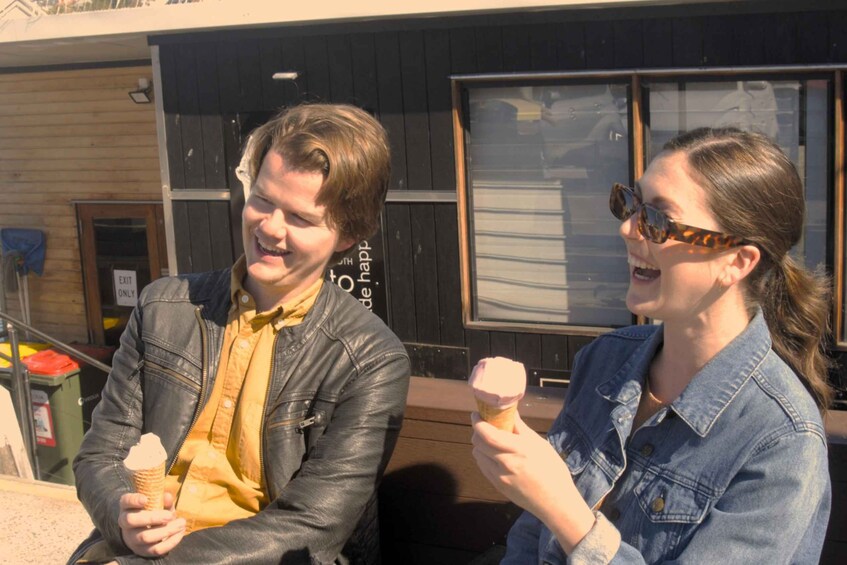 Two people sitting outdoors, one holding an ice cream cone. 4