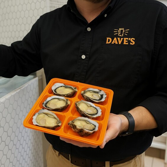 A person holding a tray with six oysters. 2