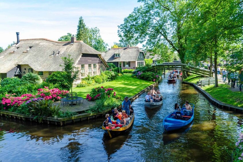 A canal with boats, houses with thatched roofs, and a bridge. 3