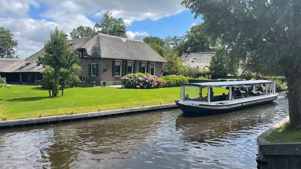 A canal with a boat named 'The Ranch' and a house with a thatched roof. 1