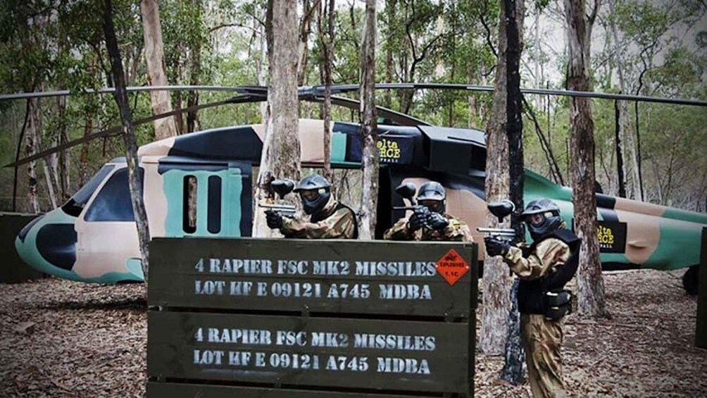 A military training area with soldiers in camouflage and helmets, a helicopter, and a sign indicating the presence of 4 Rapier FCS MK2 Missiles. 3