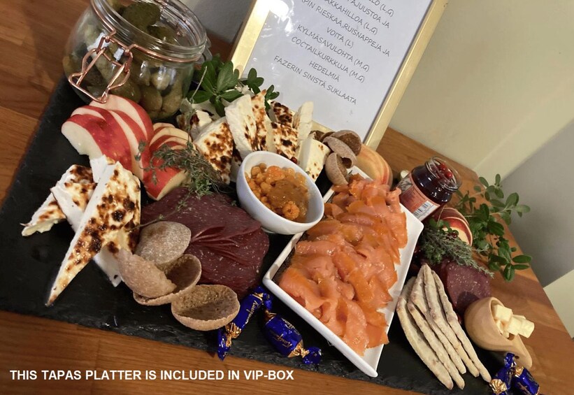 A tapas platter with various cheeses, meats, and olives on a slate board. 5