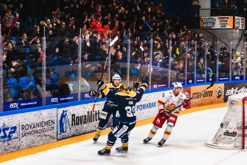 An ice hockey game with players in action, a crowd in the background, and various advertisements on the boards. 1