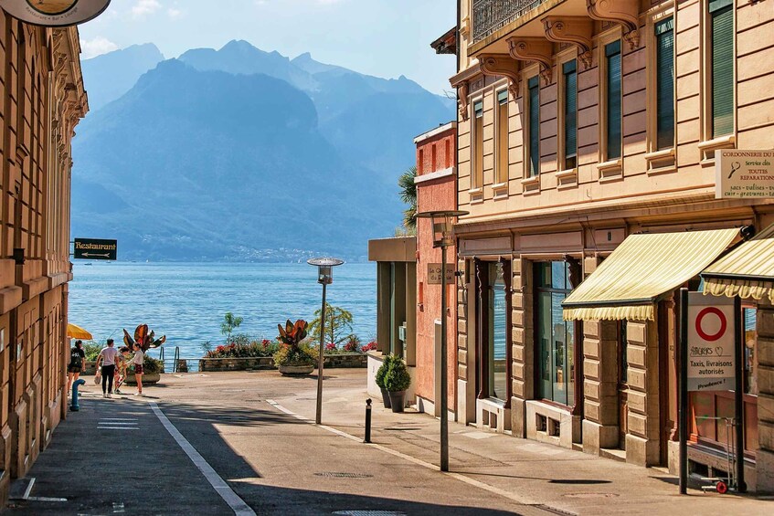 A street with buildings, a sign for a restaurant, and a view of the sea with mountains in the background. 5