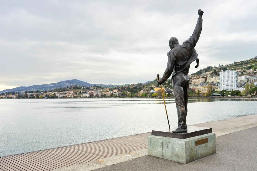 A statue of a man with a raised arm on a pedestal by a waterfront. 3