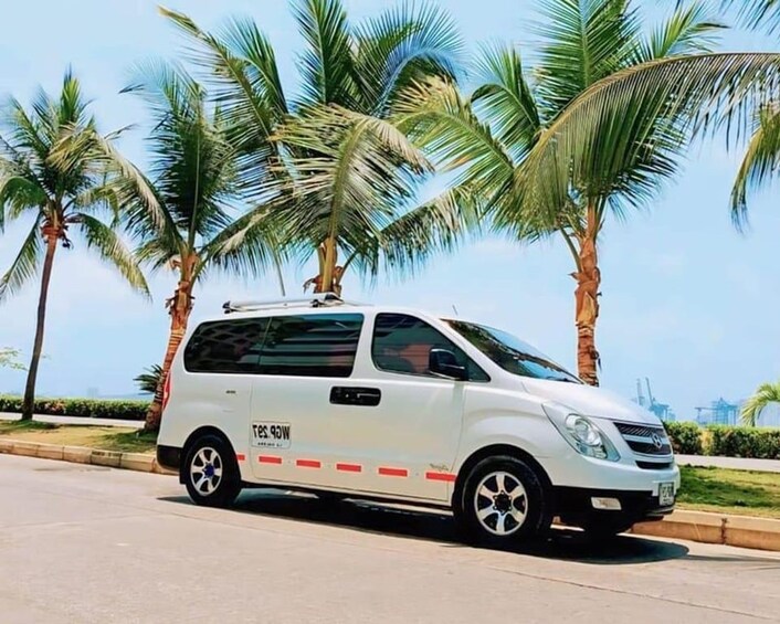 A white van parked on a road with palm trees in the background. 3
