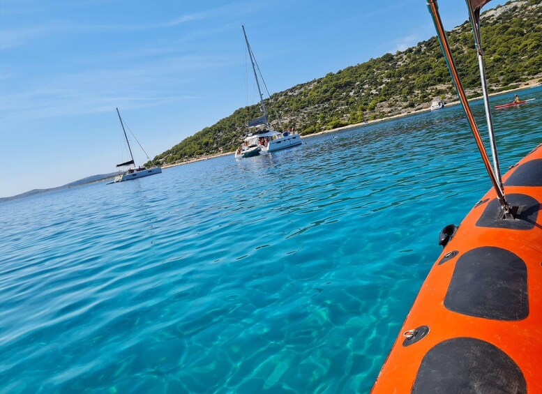 A clear blue sea with boats, a rocky coastline, and a hilly landscape. 3