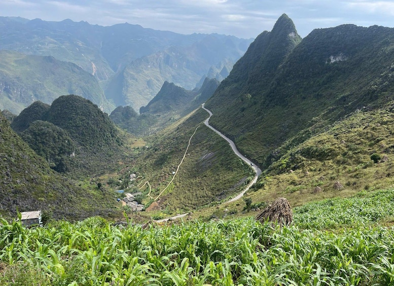 A winding road through a mountainous landscape with lush greenery and a small settlement. 5