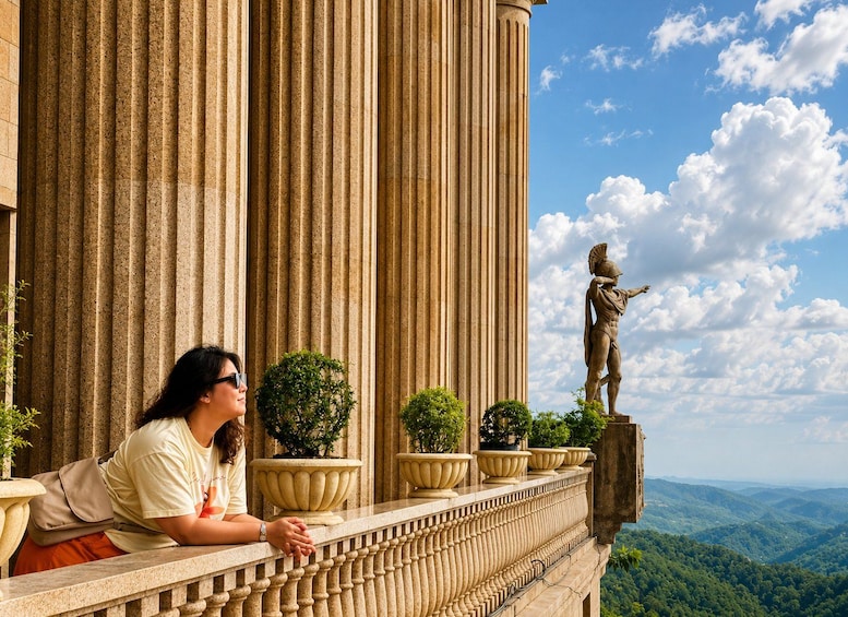 A person sitting on a balcony overlooking a large column and a statue. 4