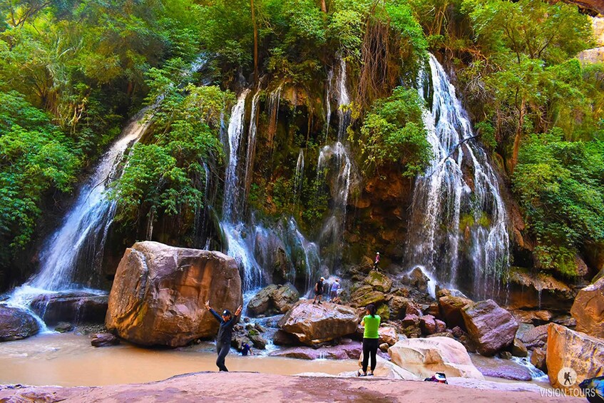 A waterfall surrounded by lush greenery and large rocks. 4