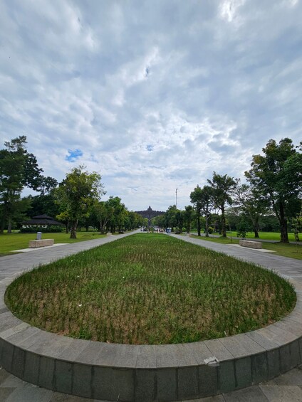 A park with a central grassy area, trees, and a distant building. 2