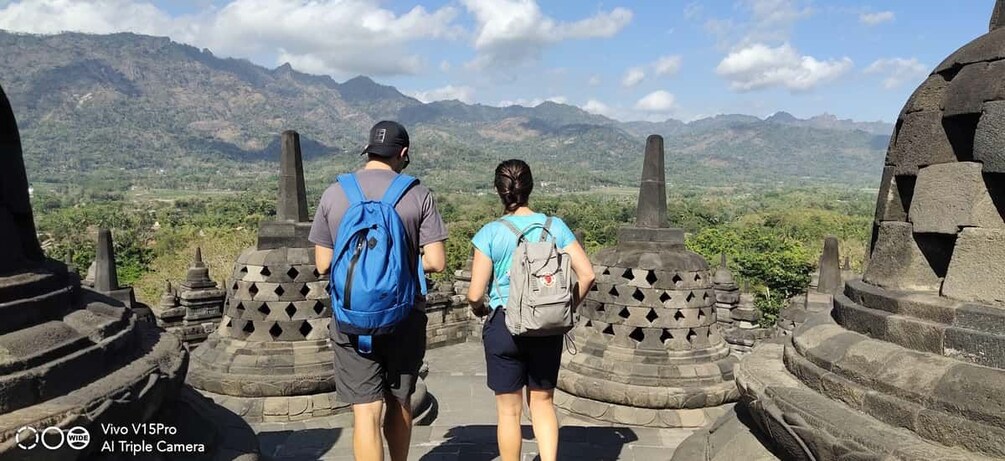 Two people walking on stone steps with a mountainous landscape in the background. 5