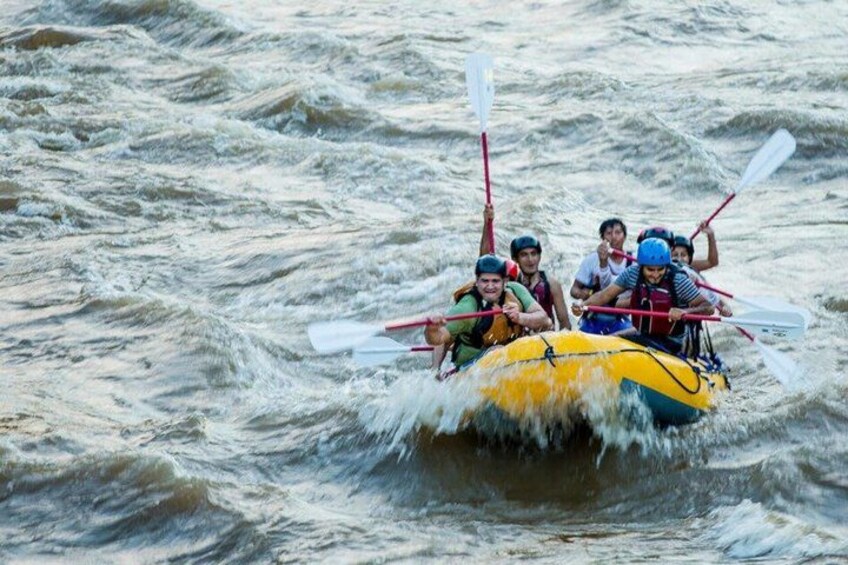 A group of people in a yellow raft navigating through rough waters. 4