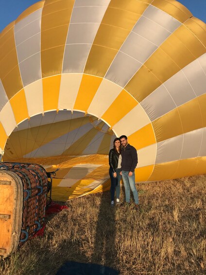 A hot air balloon with yellow and white stripes, a basket, and a ground crew. 1