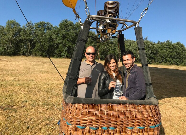 Three people in a wicker hot air balloon basket with a hot air balloon above them. 4