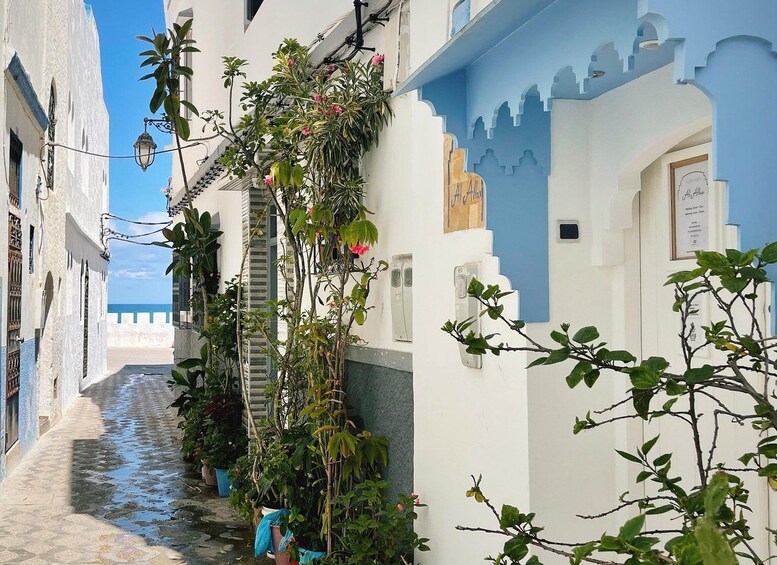 A narrow alley with white buildings, a blue door, and a staircase leading to a higher level. 2