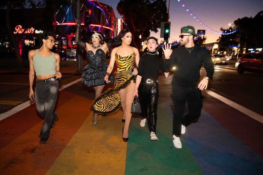 A group of people walking on a street at night with colorful lights and a neon sign in the background. 5