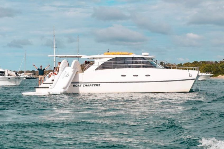 A white yacht named 'Boat Charters' with a covered deck and a small bridge, sailing on calm waters. 2