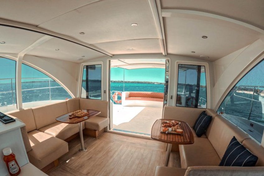 A yacht interior with a dining area, a sofa, and a view of the sea. 3