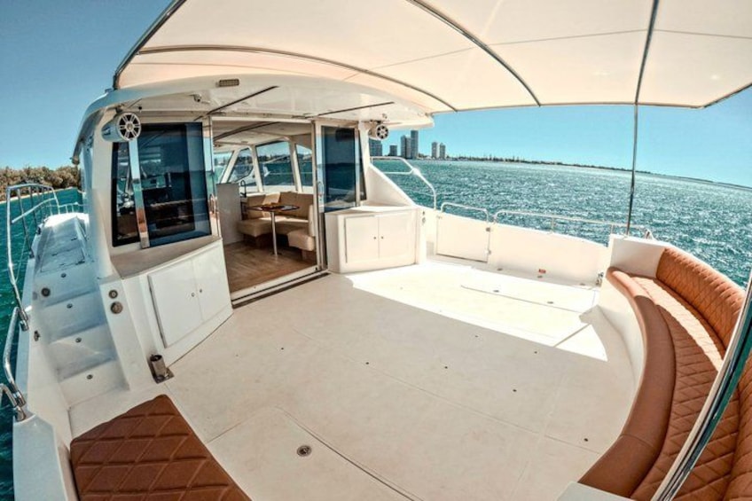 A boat deck with a covered seating area, a table, and a view of the water. 4