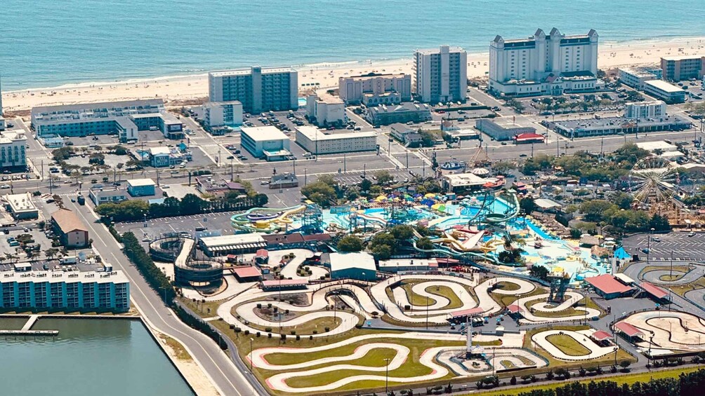 An aerial view of a coastal city with a large amusement park, a beach, and high-rise buildings. 3