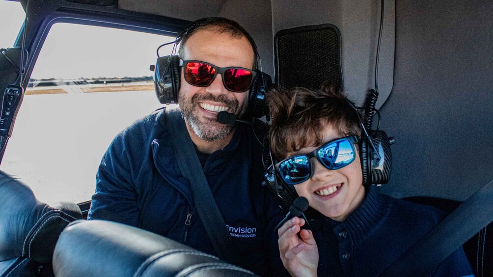 Two people in a vehicle with headsets, one holding a microphone. 4