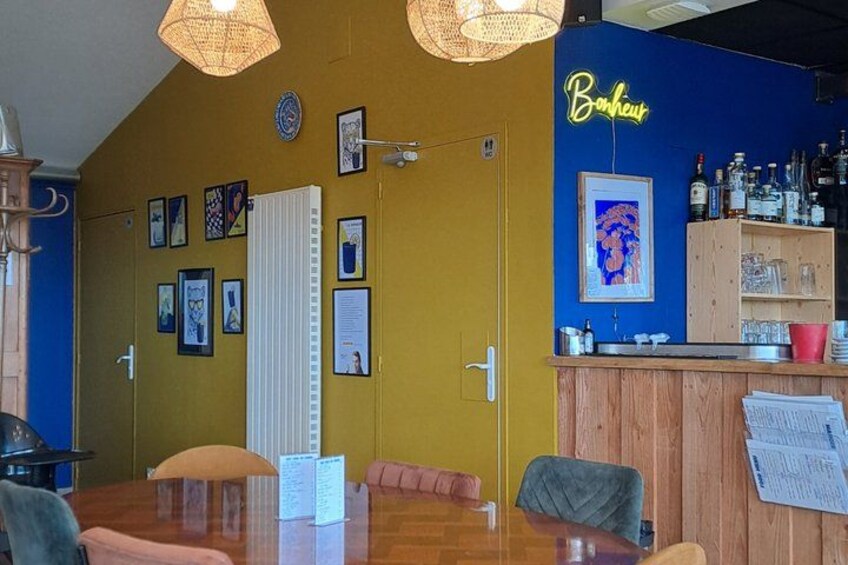 A restaurant interior with a wooden bar, yellow walls, and various framed pictures. 4