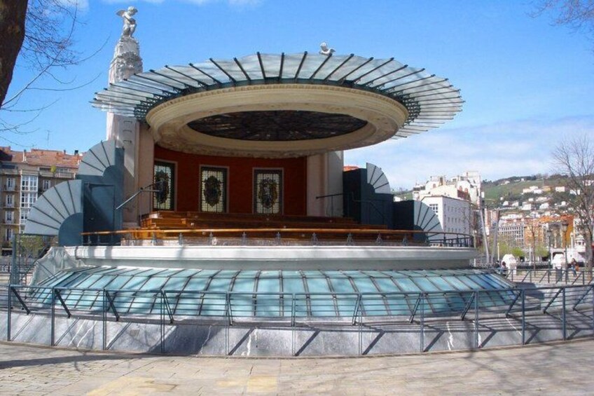 A circular building with a glass roof, a statue, and a fountain in front. 3