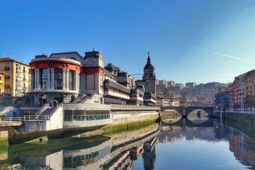 A river with a bridge, buildings, and a tower reflecting in the water. 1
