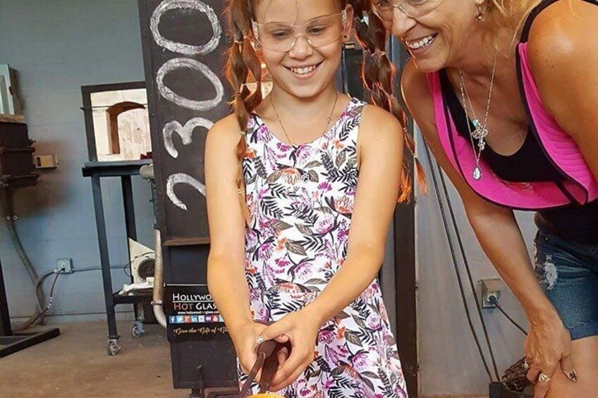 A person in a patterned dress standing in front of a chalkboard with the number '2300' written on it. 4
