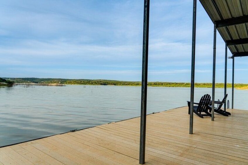 A wooden dock extending into calm water, a black chair, and a metal structure overhead. 3