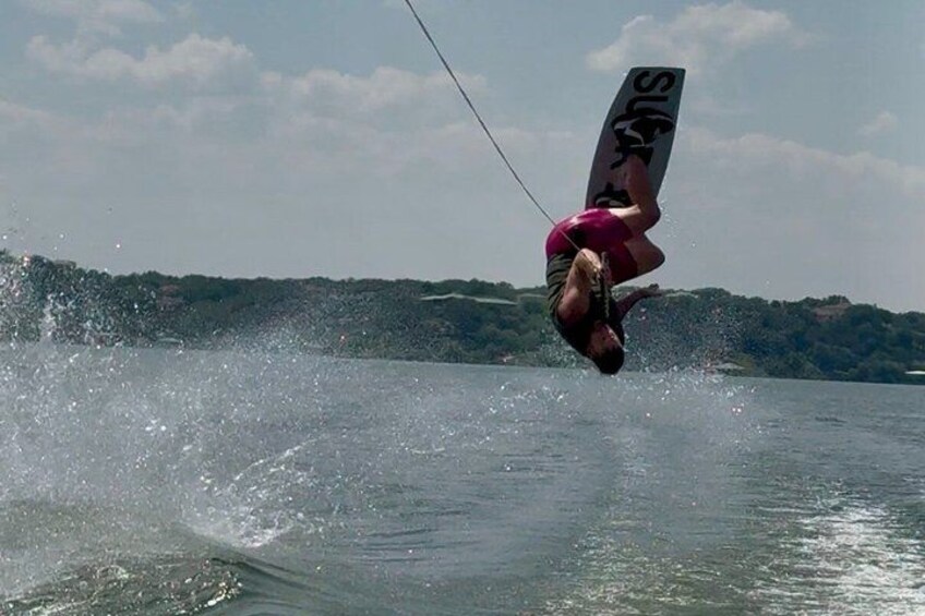 A person windsurfing, water splashing, and a lake with trees in the background. 5