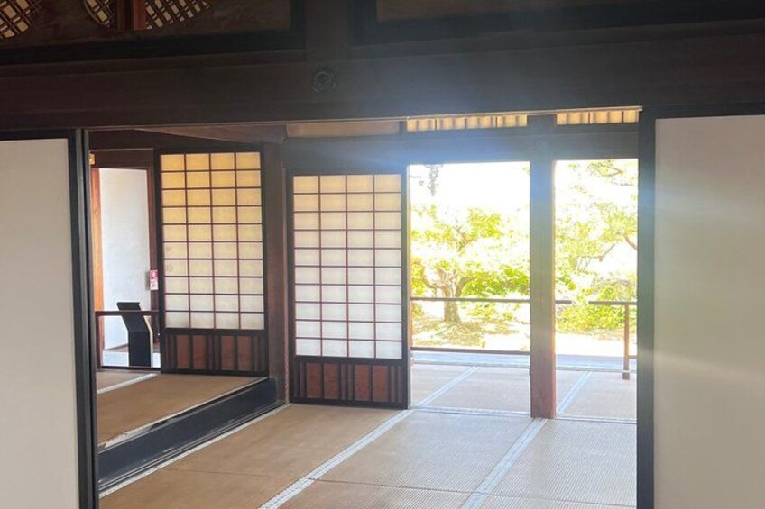 A traditional Japanese room with tatami flooring, sliding doors, and a view of a garden. 5