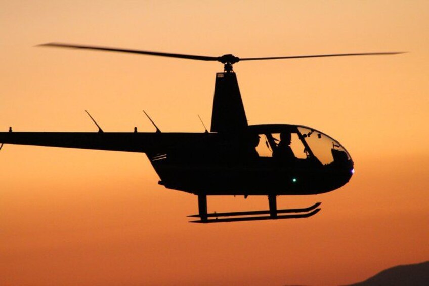 A helicopter flying against a sunset sky. 2