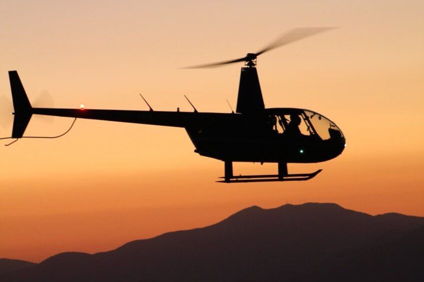 A helicopter flying over a mountainous landscape during sunset. 4
